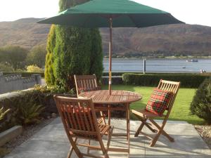 a table with two chairs and a green umbrella at Buccleuch Guest House in Fort William