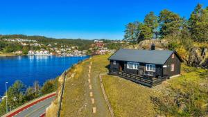 a small house on a hill next to a body of water at Vesterveien Panorama in Arendal