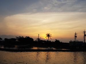枋山鄉的住宿－東隆堂旅店，棕榈树下水体上的日落