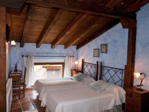 two beds in a bedroom with blue walls at Casa Rural El Encuentro in Villalón de Campos