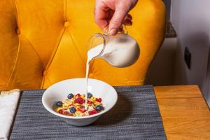 una persona vertiendo leche en un tazón de cereales en Hotel Royal Inn, en Belgrado