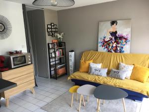 a living room with a yellow couch and a painting at Appartement T2 refait à neuf, piscine in Quiberon