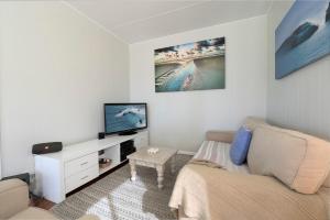 a living room with a couch and a tv at Tallowood beachfront cottage in Bonny Hills