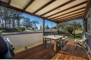 Un patio con una mesa y sillas en una terraza. en Tallowood beachfront cottage, en Bonny Hills