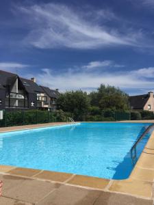 a large blue swimming pool with houses in the background at Appartement T2 refait à neuf, piscine in Quiberon