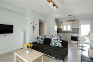 a living room with a black couch and a kitchen at Bright Spacious Two-Bedroom Apartment in Thessaloniki