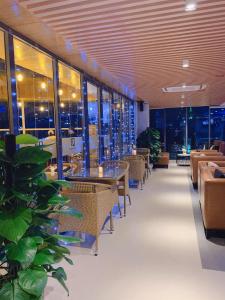 restauracja ze stołami, krzesłami i oknami w obiekcie Quốc Thanh Hotel w mieście Long Khanh