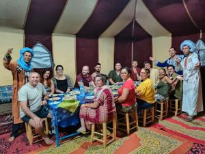 a group of people sitting at a table in a room at Desert Camp Erg Chebbi in Merzouga