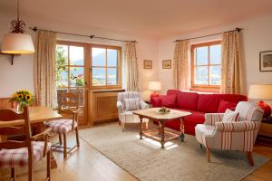 a living room with a red couch and chairs at Landsitz Römerhof - Hotel Apartments in Kitzbühel