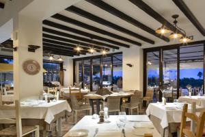 a restaurant with white tables and chairs and windows at Hotel Abi d'Oru in Porto Rotondo