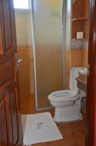 a bathroom with a toilet and a glass shower at Pavilion Holiday Resort in Bamburi