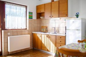 uma cozinha com armários de madeira e um frigorífico branco em Apartments Belavic em Njivice
