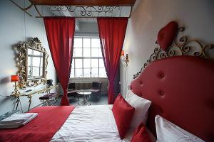 
a bedroom with a red bedspread and red curtains at Blue Collar Hotel in Eindhoven
