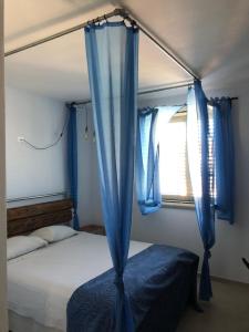 a bedroom with a bed with blue curtains and a window at il Mandriolo in Marina di Grosseto