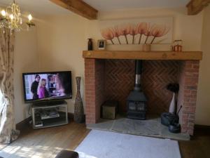 sala de estar con TV y chimenea en Measure Cottage - Sleeps 5 - Private Hot tub and garden en Henley in Arden