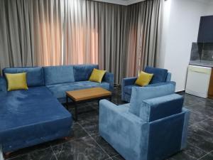 a living room with a blue couch and two chairs at Sirena Apart & SPA in Antalya
