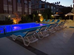 a group of chairs and a swimming pool at night at Sirena Apart & SPA in Antalya