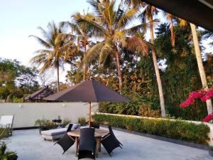 a patio with a table and chairs and palm trees at Omah SunFlower in Yogyakarta