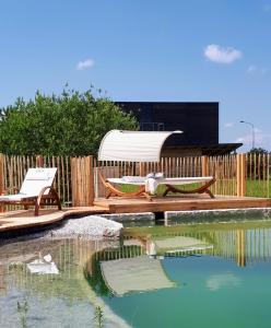 uma piscina com duas cadeiras e um gazebo em Hotel der Freiraum em Güssing