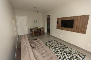 a living room with a couch and a television on a wall at Hotel do Bosque in Balneário Camboriú