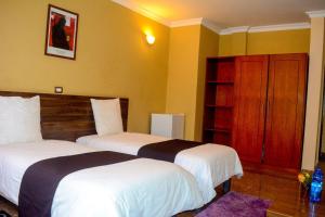 Duas camas num quarto com paredes amarelas em Melodie Hotel em Addis Ababa