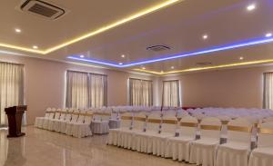 um salão de banquetes com filas de cadeiras e um pódio em Hotel RK Gardenia em Bangalore