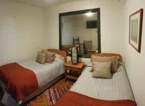 a bedroom with two beds and a mirror at Hostal Centro Montt in Temuco
