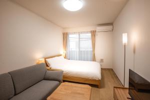 a bedroom with a bed and a couch and a window at H2O Stay Ikebukuro in Tokyo