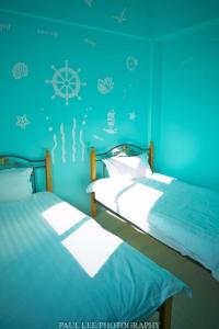2 camas individuales en una habitación con paredes azules en Sronghld 128 B&B en Jinning