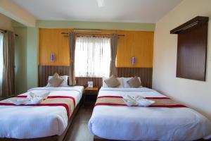 a hotel room with two beds and a window at Hotel Guru in Pokhara