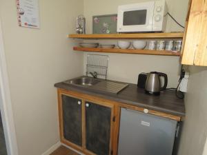 a small kitchen with a sink and a microwave at Fairview Cottages in Clarens