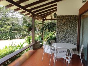 a table and chairs on a porch with a stone wall at Finca Paraíso in Calima