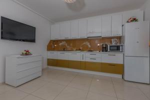 a kitchen with white cabinets and a white refrigerator at Villa Rossa Apartments in Rab