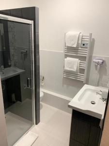 a white bathroom with a shower and a sink at Hotel Růžek in Hranice
