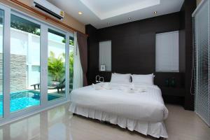 
a hotel room with a large bed and a large window at The Ville Jomtien Pool Villa in Jomtien Beach
