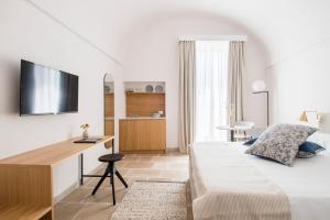 a bedroom with a bed and a desk with a television at Palazzo Mulini in Monopoli