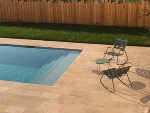 two chairs and a table next to a swimming pool at Le Loft Deveney-Mars in Puligny-Montrachet