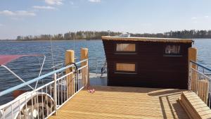 uma doca de madeira com um pequeno edifício sobre a água em Hausboot Krakow am See Forelle 1 und 2 em Krakow am See