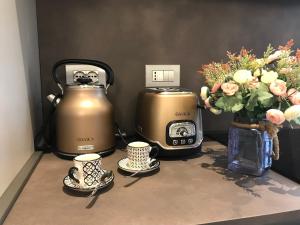 two kettles and a toaster and two cups and flowers at Piccola Dimora in Negrar