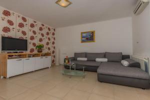 sala de estar con sofá y TV en Villa Marija Apartments, en Rab