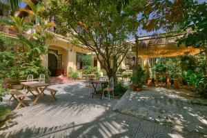 a patio with tables and chairs and a tree at Le Robinet Homestay in Hue