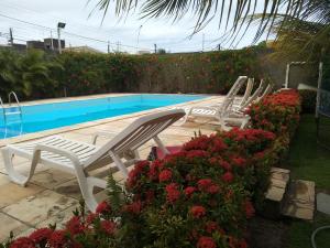 two white lawn chairs sitting next to a swimming pool at Flat Julieta in Paulista