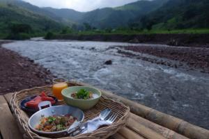 a picnic table with a bowl of food next to a river at ต้นน้ำน่าน บ่อเกลือ in Ban Sale