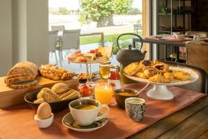 ein Frühstückstisch mit Brot, Gebäck und Orangensaft in der Unterkunft Oversteekhof in Roesbrugge-Haringe