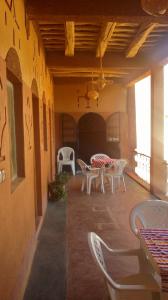 a patio with white chairs and tables in a building at Auberge Des Jardins du Dades in Boumalne