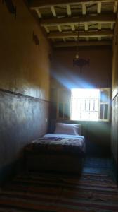 a bedroom with a bed in a room with a window at Auberge Des Jardins du Dades in Boumalne