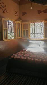 a bedroom with a bed and two windows at Auberge Des Jardins du Dades in Boumalne