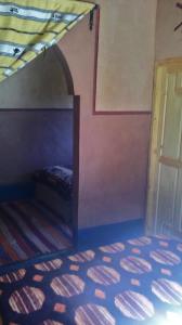 a bedroom with a bed and a wall with a door at Auberge Des Jardins du Dades in Boumalne