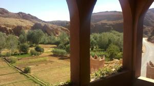 a view from a window of a field and mountains at Auberge Des Jardins du Dades in Boumalne