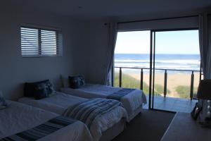 a bedroom with two beds and a balcony with the ocean at Oyster bay beach house in Oyster Bay